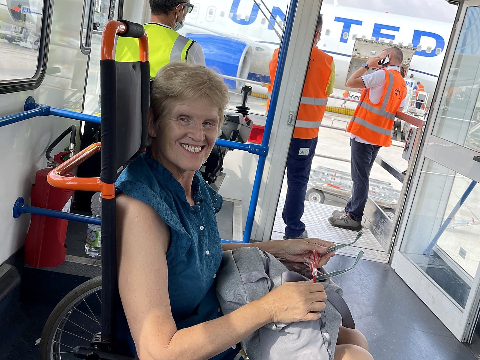 A smiling patient in a wheelchair being brought to the aircraft door on a CME medical escort mission